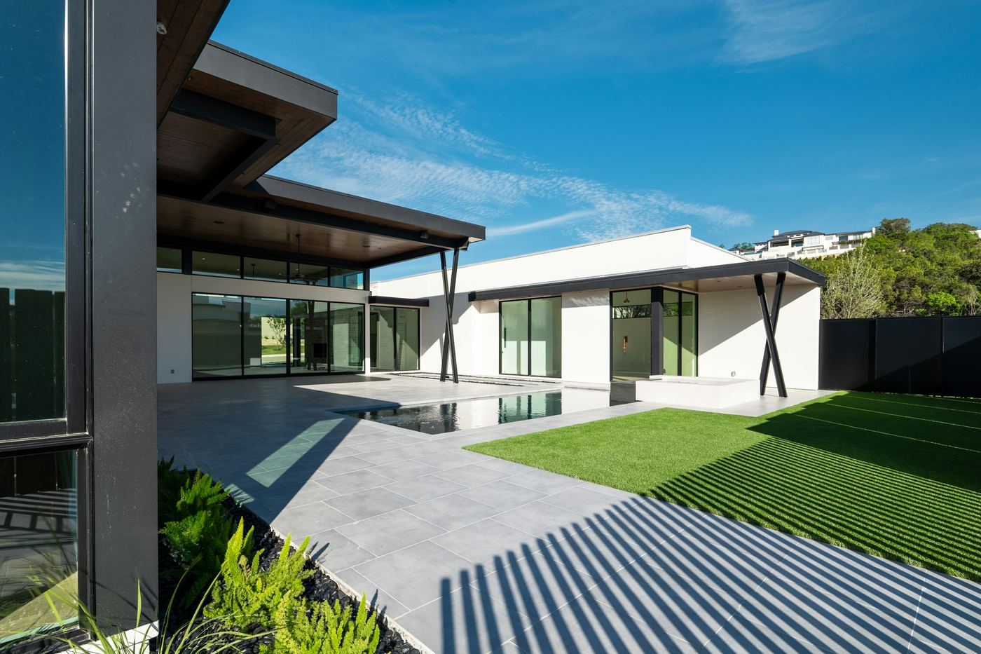 Modern single-storey house with a long pool and lawn