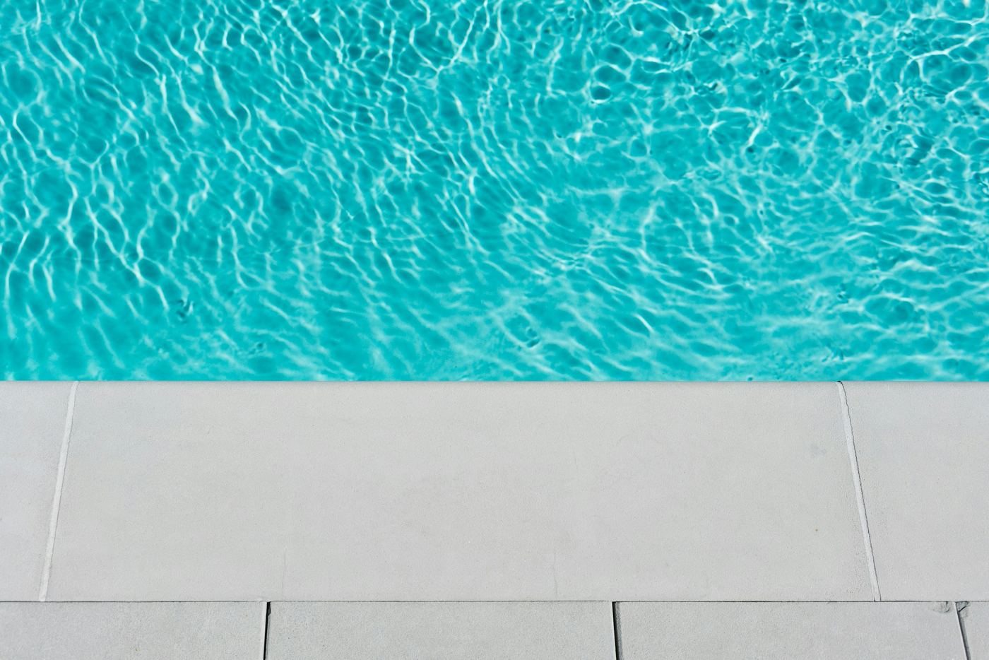 Clear pool water beside pale stone coping