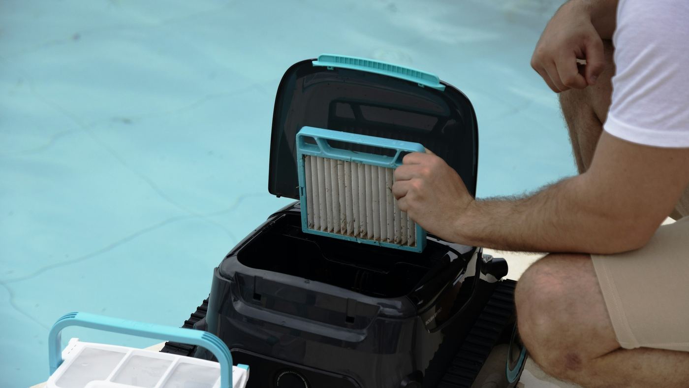 A technician cleaning the filter of a robotic pool cleaner