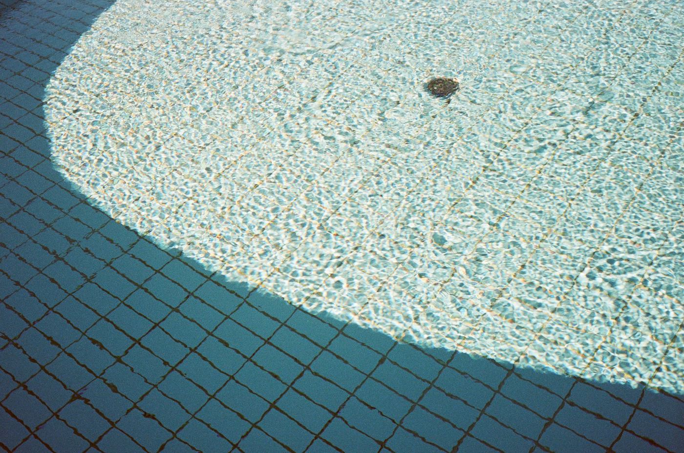 A curved shadow falling across the floor of a pool